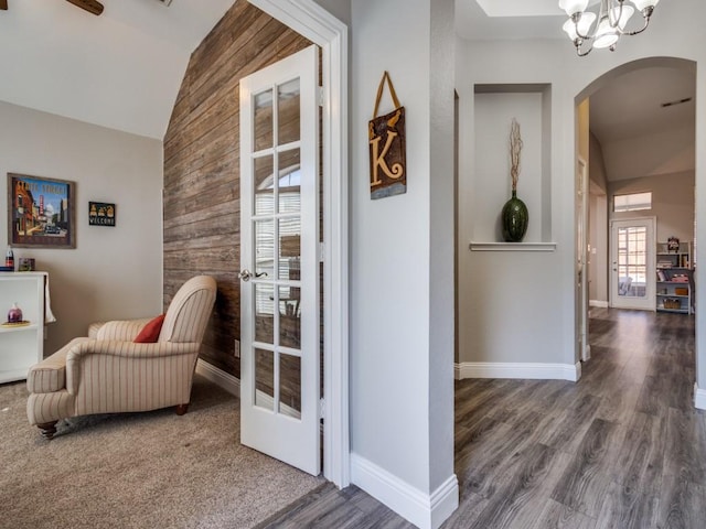 sitting room featuring arched walkways, wood walls, lofted ceiling, and baseboards