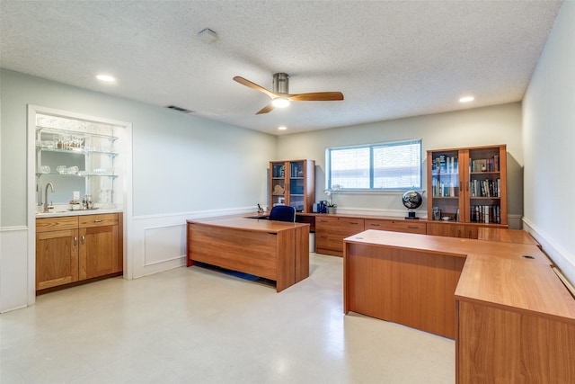 home office featuring a textured ceiling, ceiling fan, recessed lighting, a sink, and visible vents