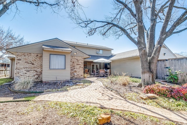 back of house featuring a patio, brick siding, and fence