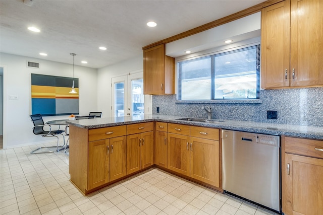 kitchen featuring visible vents, brown cabinetry, a peninsula, stainless steel dishwasher, and a sink