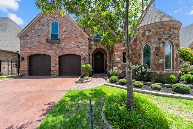 view of front facade with brick siding, roof with shingles, fence, a garage, and driveway