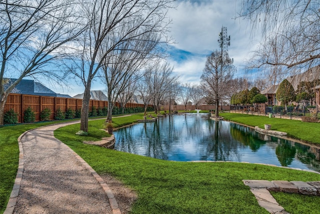 view of community with a water view, fence, and a yard