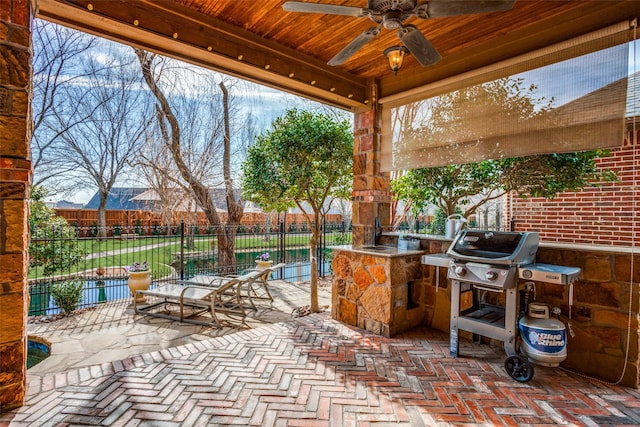 view of patio featuring exterior kitchen, fence, grilling area, and a ceiling fan