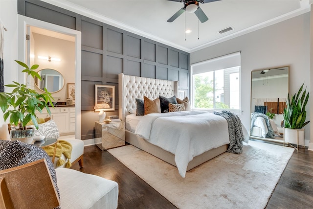 bedroom featuring ensuite bathroom, a decorative wall, dark wood-style flooring, visible vents, and ornamental molding