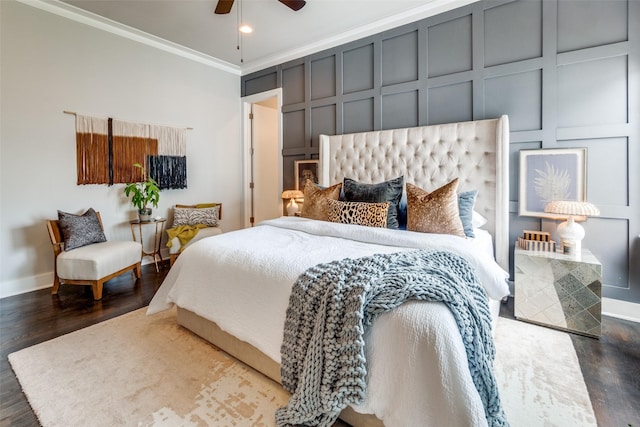 bedroom featuring dark wood-type flooring, crown molding, a decorative wall, and baseboards