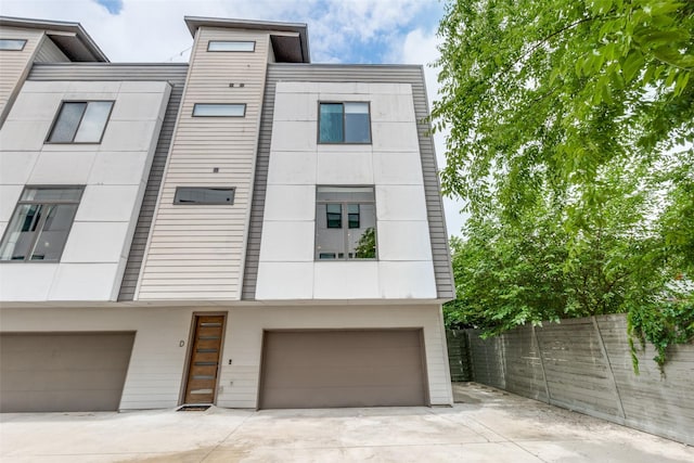 view of front of house featuring driveway, an attached garage, and fence