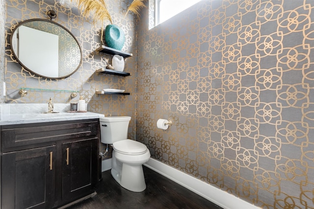 bathroom with baseboards, vanity, toilet, and wood finished floors