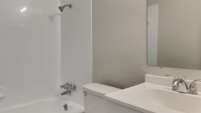 full bathroom with toilet, vanity,  shower combination, and a textured wall