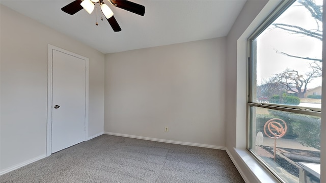 empty room featuring carpet, baseboards, and a ceiling fan