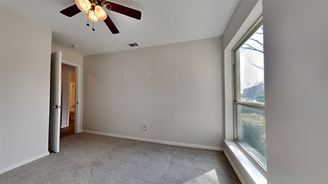 unfurnished room featuring carpet, visible vents, ceiling fan, a textured ceiling, and baseboards