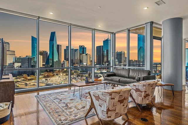 living area featuring a view of city, visible vents, wood finished floors, and floor to ceiling windows