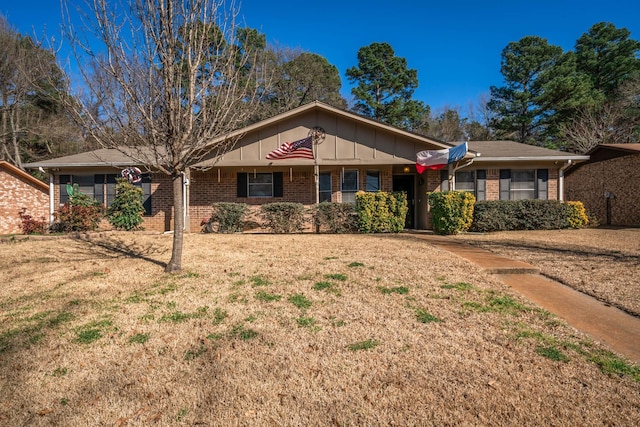 single story home featuring a front lawn, board and batten siding, and brick siding