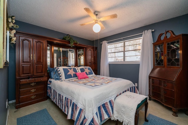 bedroom with a ceiling fan, light carpet, and a textured ceiling