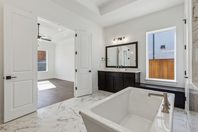 full bathroom with a ceiling fan, vanity, a freestanding bath, marble finish floor, and baseboards