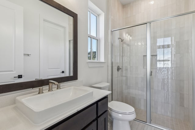 bathroom featuring a shower stall, toilet, and vanity