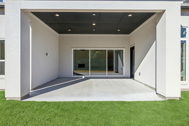 rear view of property featuring a patio area, a yard, and stucco siding