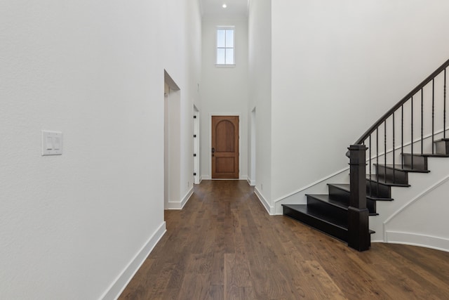 foyer featuring stairs, a high ceiling, wood finished floors, and baseboards