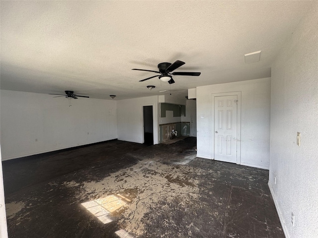 unfurnished living room featuring ceiling fan, a textured ceiling, baseboards, and unfinished concrete floors