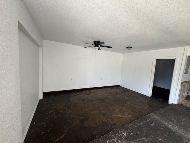 empty room with ceiling fan, unfinished concrete floors, baseboards, and a textured ceiling