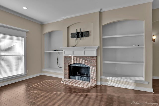 unfurnished living room featuring built in shelves, a fireplace, ornamental molding, wood finished floors, and baseboards