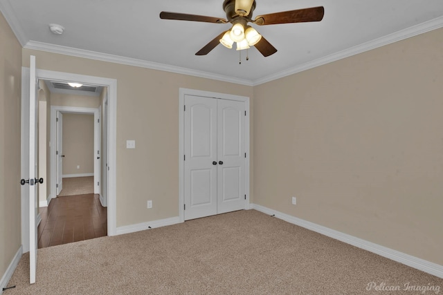 unfurnished bedroom featuring carpet floors, visible vents, baseboards, a closet, and crown molding