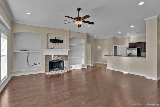 unfurnished living room with built in features, dark wood finished floors, visible vents, a brick fireplace, and baseboards