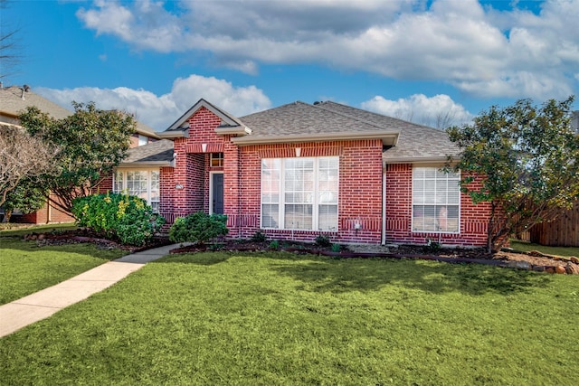 ranch-style house with roof with shingles, brick siding, a front lawn, and fence