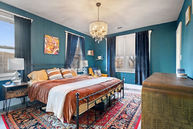 bedroom featuring baseboards, multiple windows, visible vents, and a chandelier