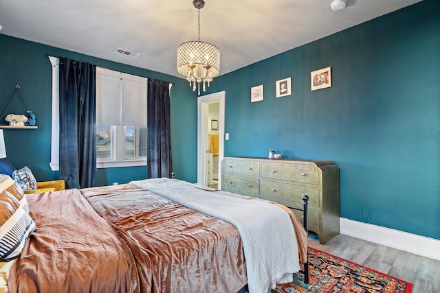 bedroom featuring a chandelier, wood finished floors, visible vents, and baseboards