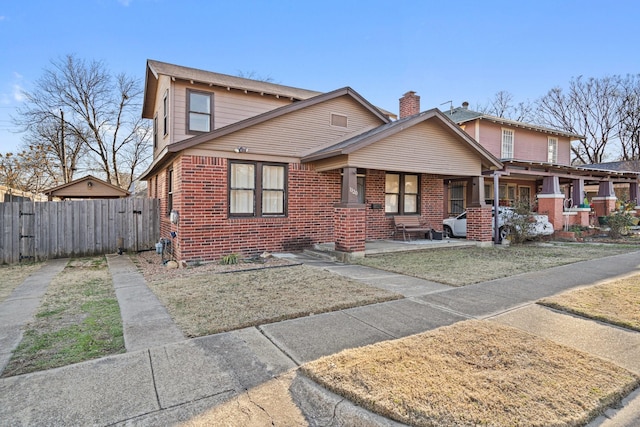 view of front of home featuring fence, a porch, and brick siding