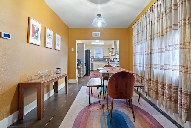 dining space featuring baseboards, visible vents, and dark tile patterned flooring