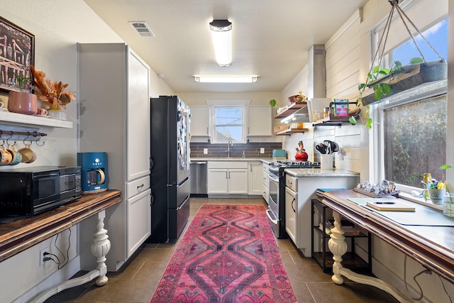 kitchen with a sink, white cabinetry, appliances with stainless steel finishes, backsplash, and open shelves