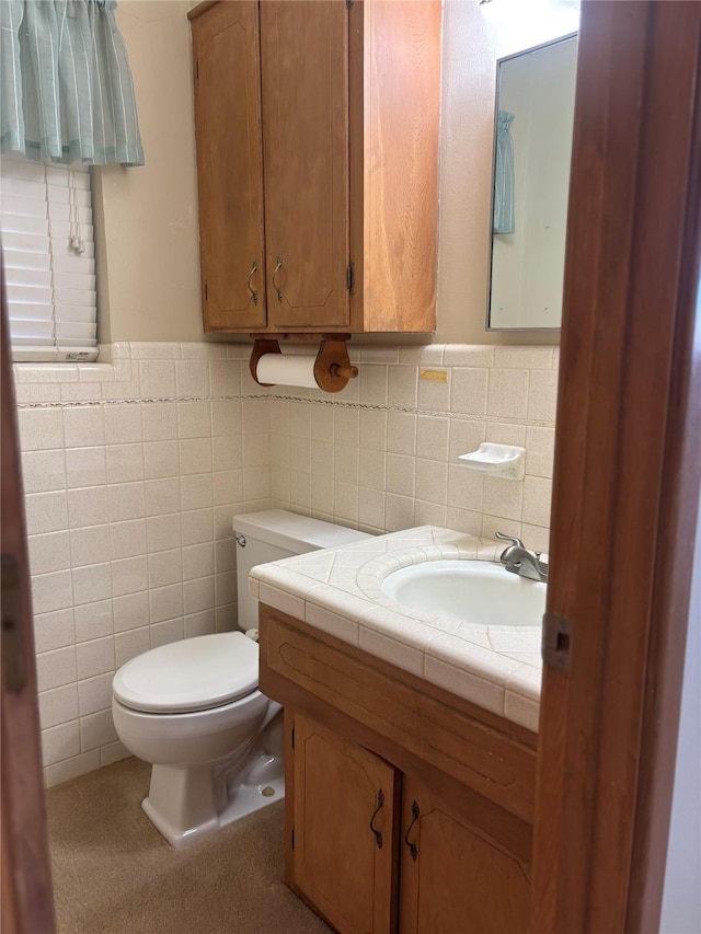 bathroom with a wainscoted wall, tile walls, toilet, and vanity