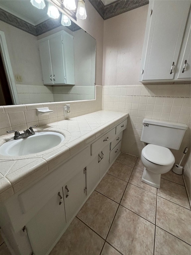 bathroom featuring toilet, tile patterned flooring, tile walls, and vanity
