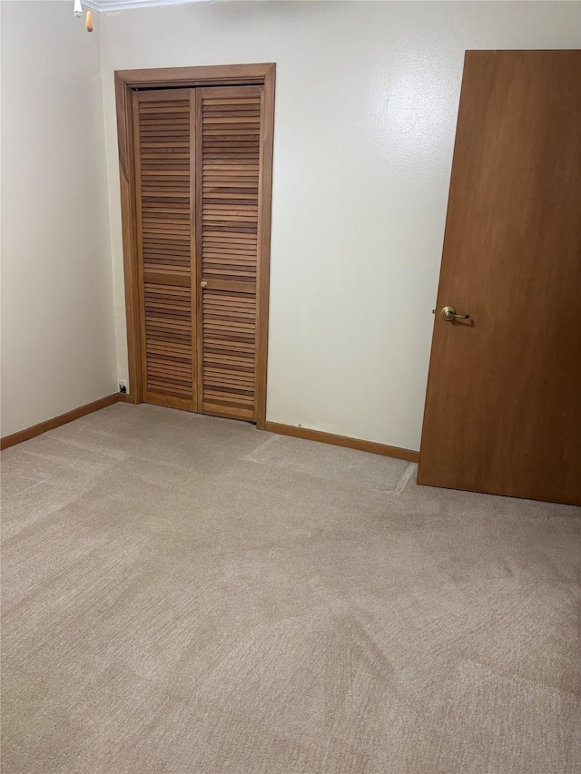 unfurnished bedroom with a closet, baseboards, and carpet flooring