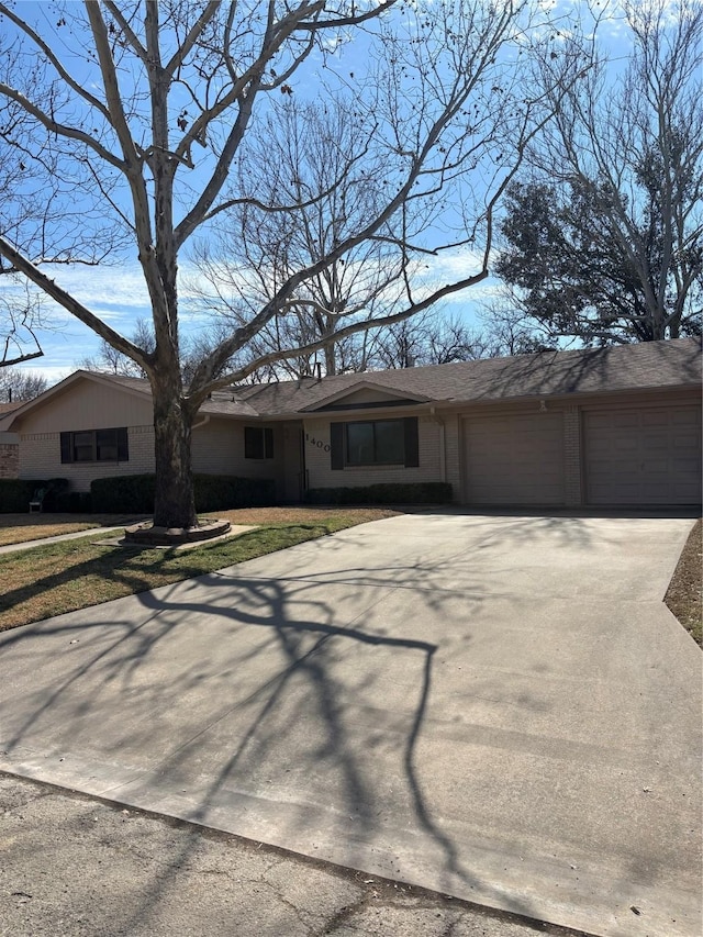 view of front of home featuring a garage, concrete driveway, and brick siding