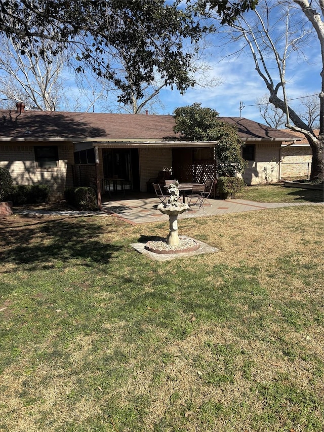 rear view of property with brick siding, a patio, and a lawn
