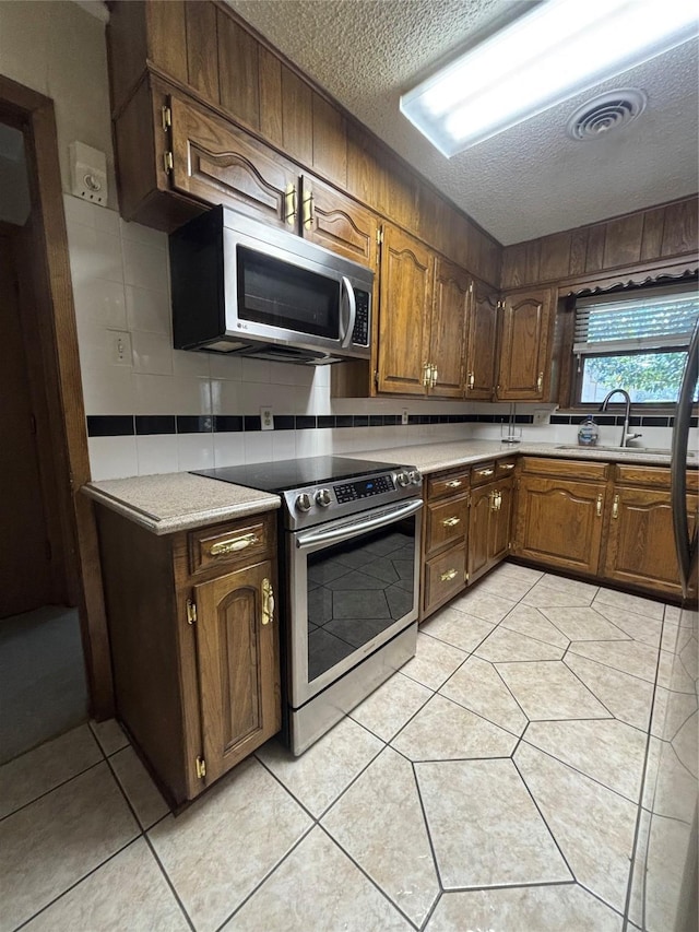 kitchen with stainless steel appliances, visible vents, light countertops, a sink, and a textured ceiling
