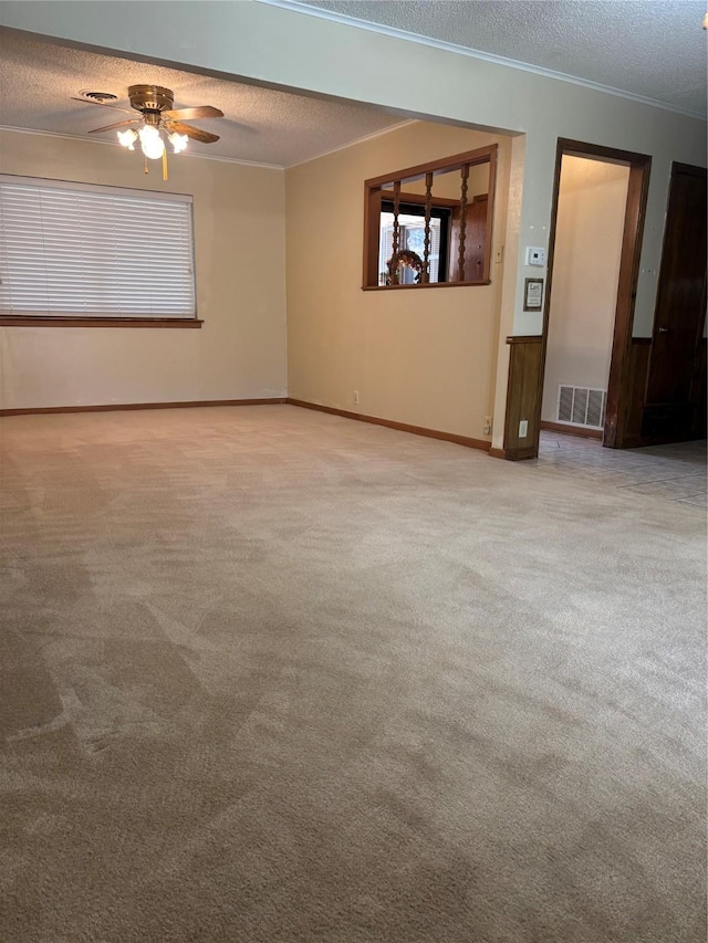 spare room featuring visible vents, a ceiling fan, ornamental molding, a textured ceiling, and carpet floors