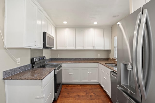 kitchen with dark wood-style floors, appliances with stainless steel finishes, white cabinetry, a sink, and recessed lighting