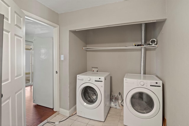 washroom with washer and dryer, laundry area, baseboards, and light tile patterned floors