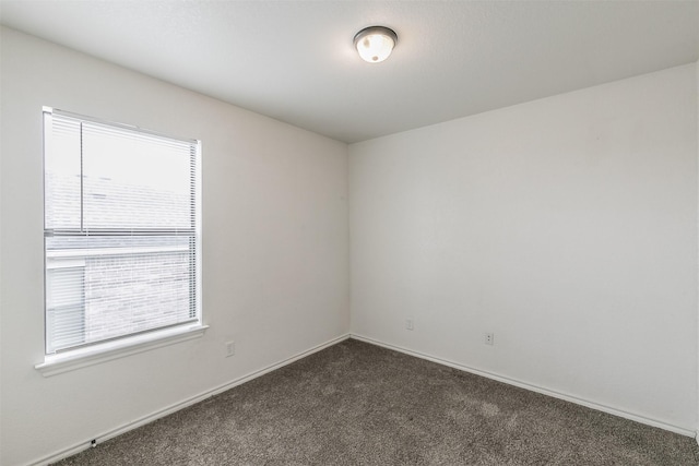 unfurnished room with dark carpet and baseboards