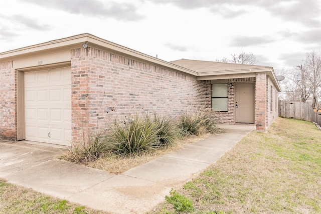 exterior space with a front lawn, brick siding, fence, and an attached garage