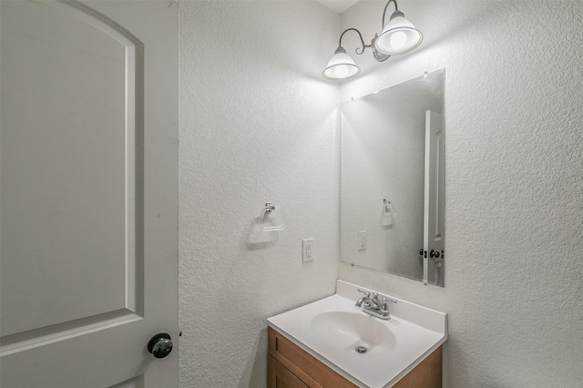 bathroom with a textured wall and vanity