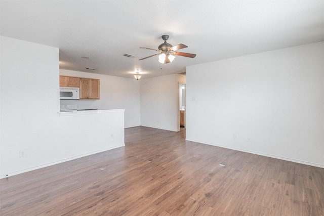 unfurnished living room featuring visible vents, wood finished floors, a ceiling fan, and baseboards