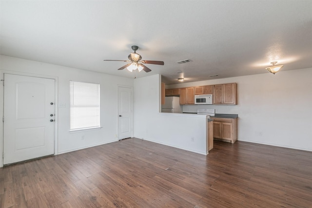 kitchen with white appliances, visible vents, brown cabinetry, dark wood-style flooring, and a peninsula