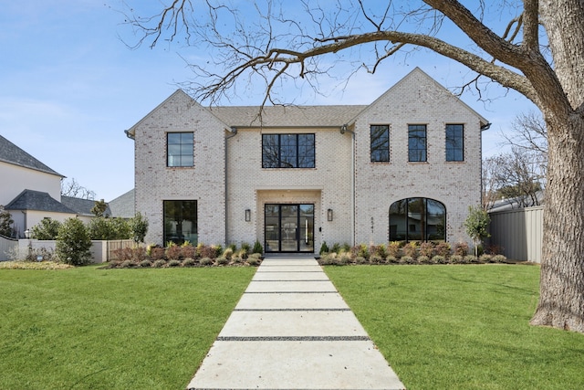 view of front of house featuring french doors, brick siding, a front yard, and fence