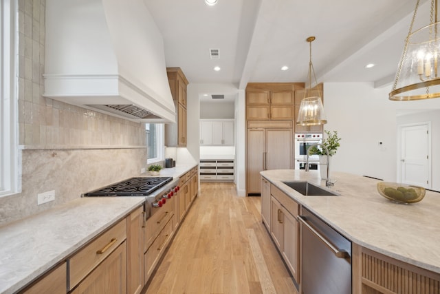 kitchen with custom exhaust hood, tasteful backsplash, light wood-style flooring, appliances with stainless steel finishes, and a sink