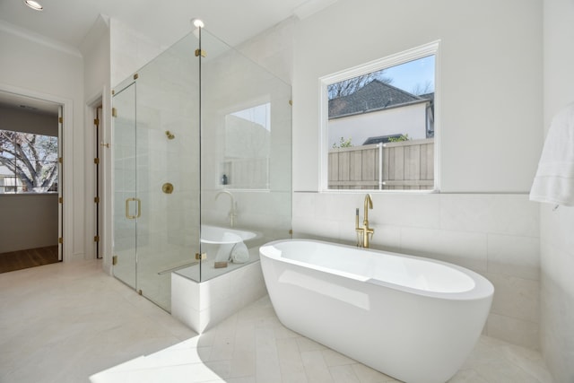 full bath featuring recessed lighting, tile walls, a soaking tub, a stall shower, and crown molding