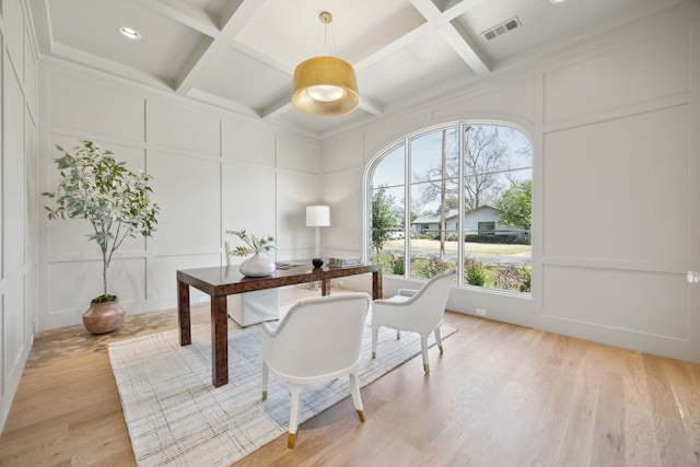 home office featuring a decorative wall, coffered ceiling, visible vents, light wood-style floors, and beamed ceiling